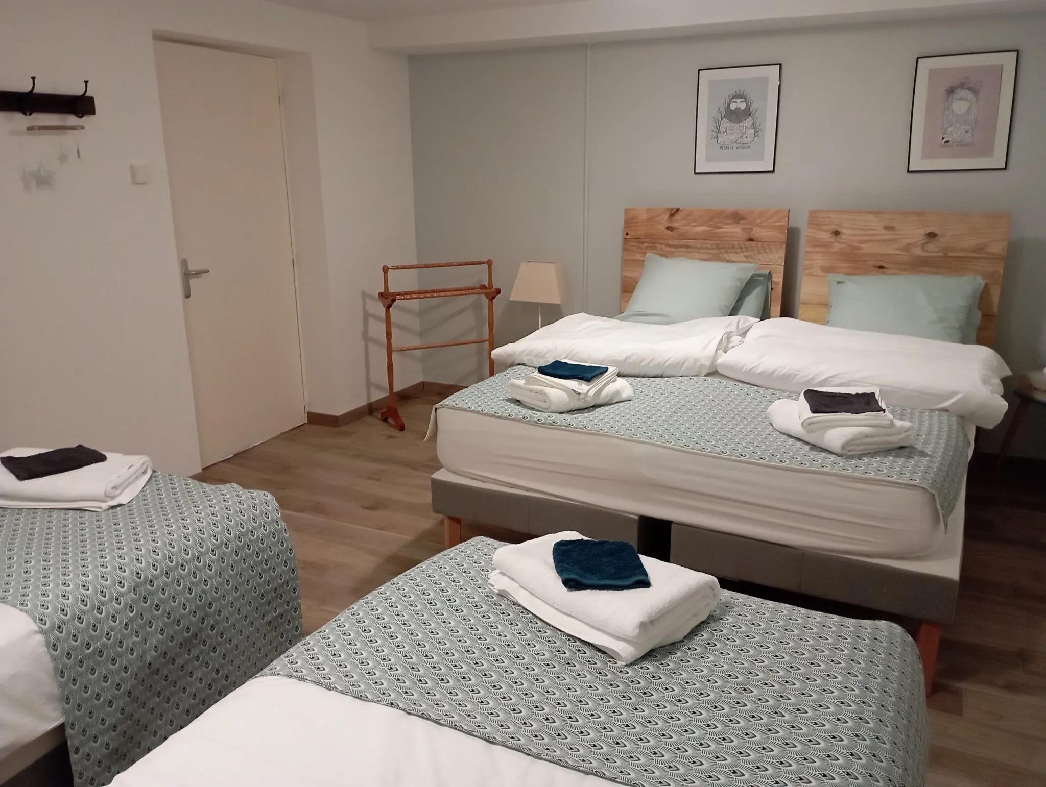Chambre familiale du gîte aménagée avec plusieurs lits côte à côte, serviettes pliées sur chaque lit.