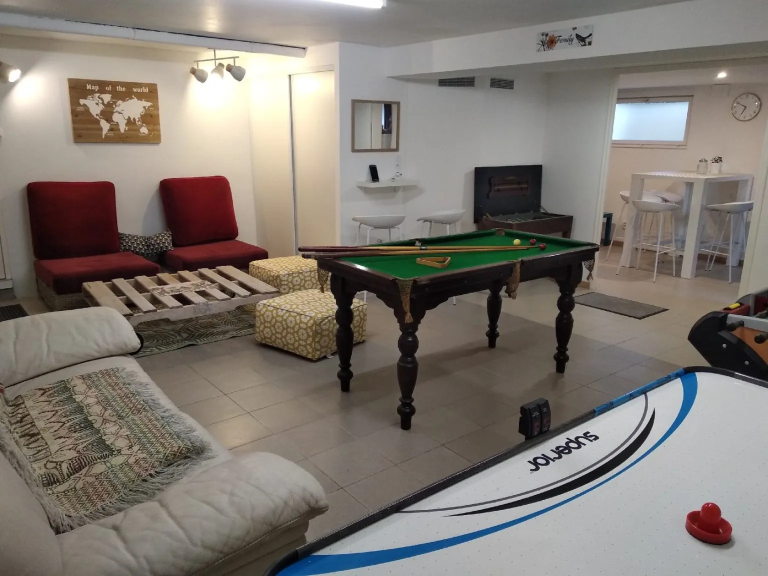Salle de jeux du gîte avec billard, table d’air hockey, baby-foot et coin canapés.